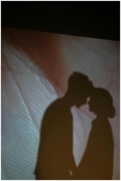 Shadowy silhouette of a kissing couple against a t