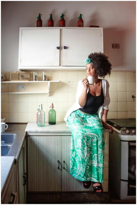 Woman sitting on kitchen counter enjoying a warm c