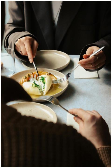 Two adults enjoying a shared gourmet dish at a sty