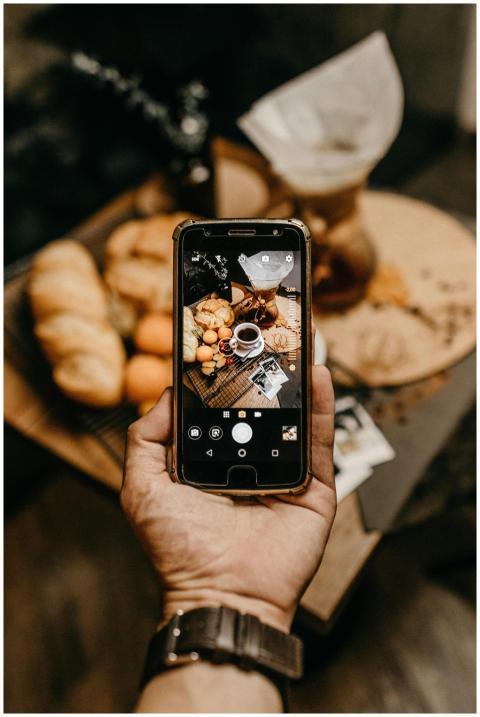 Warm indoor scene with smartphone capturing coffee