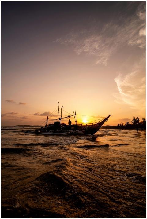 Fishermen sail a traditional boat at sunset on Wel