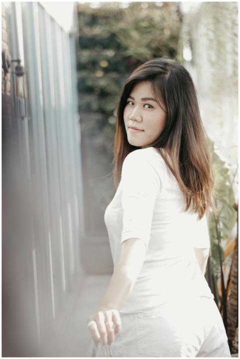 Stylish Asian woman in white looks back with a smi