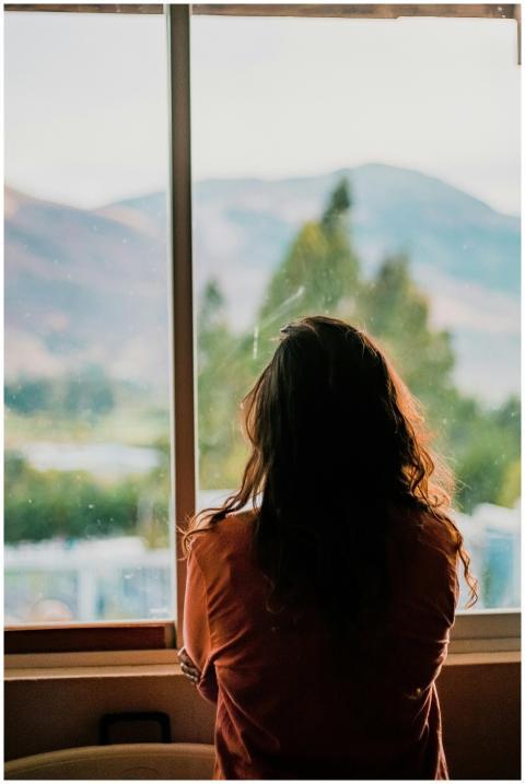 Silhouette of a woman looking out a window at a sc