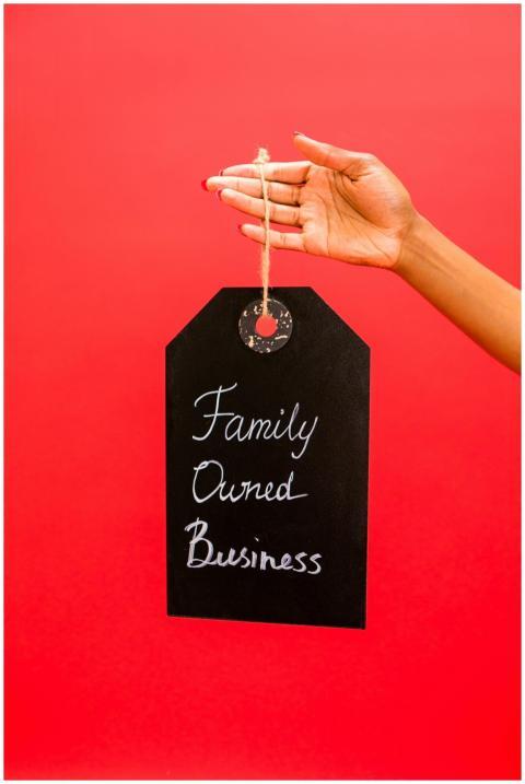 Hand holding a chalkboard sign reading 'Family Own