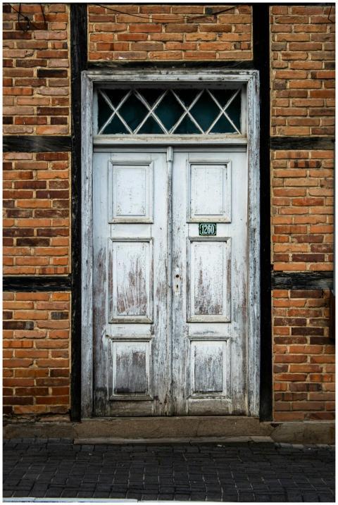 A weathered, vintage wooden door set in a brick wa