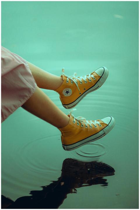 Yellow sneakers creating ripples on a serene water