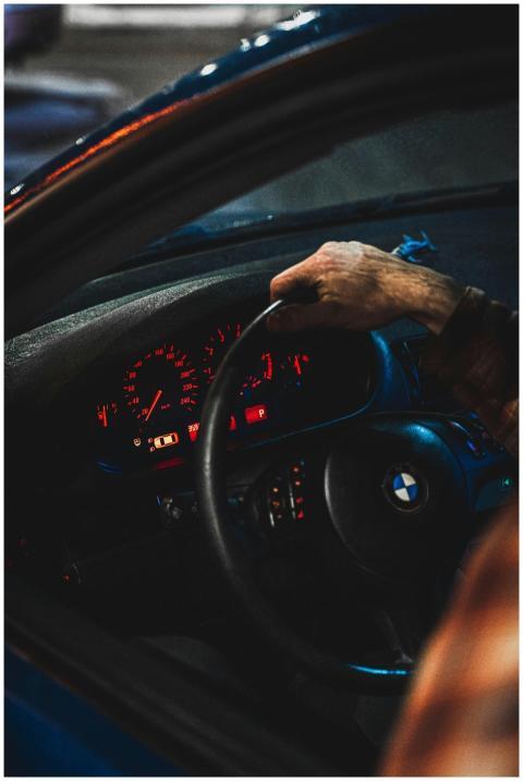 A hand gripping a BMW steering wheel with illumina