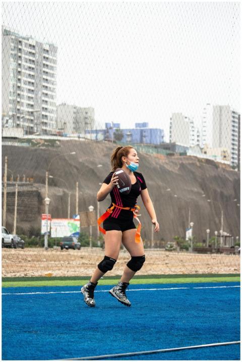 A woman in sportswear plays flag football on an ou