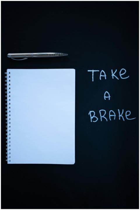 Flat lay of a white notebook, pen, and 'Take a Bra