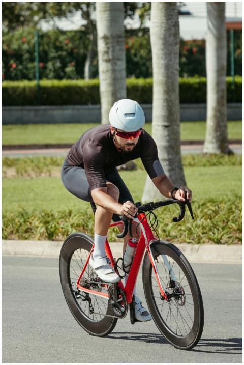 A male cyclist in athletic gear rides a red bike o
