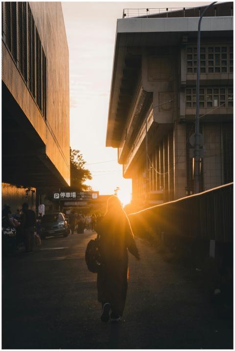 Person walking at sunset between buildings, captur