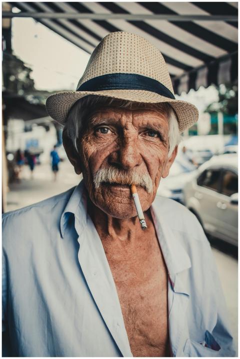 Portrait of an elderly man wearing a hat and smoki