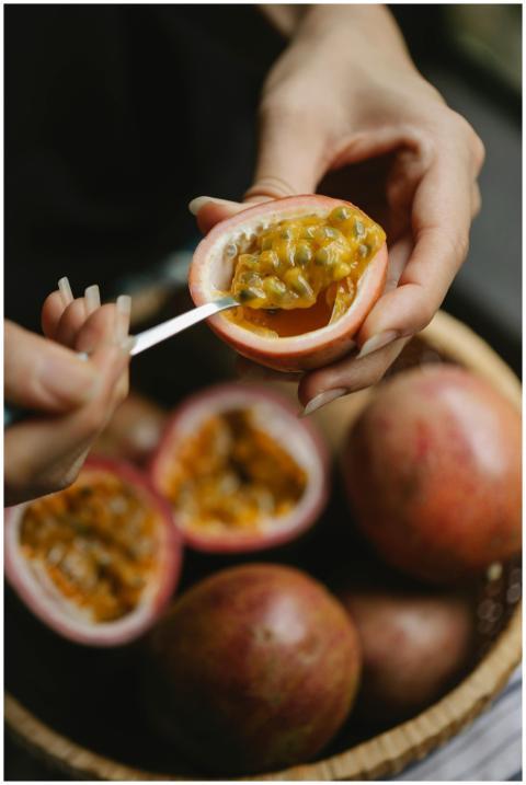 Crop woman spooning out pulp of ripe juicy passion
