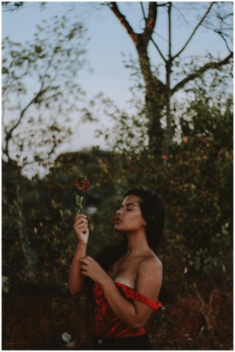 A woman in a red dress embraces nature in an outdo