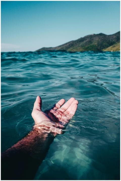 A serene hand emerges from the vibrant ocean waves