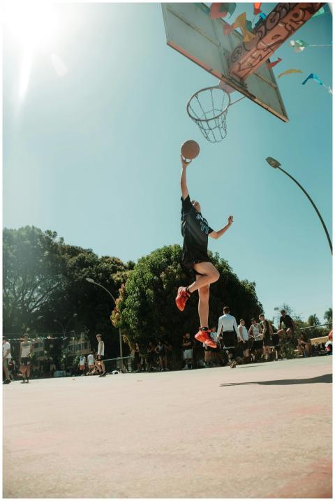 A vibrant outdoor basketball game with a player du