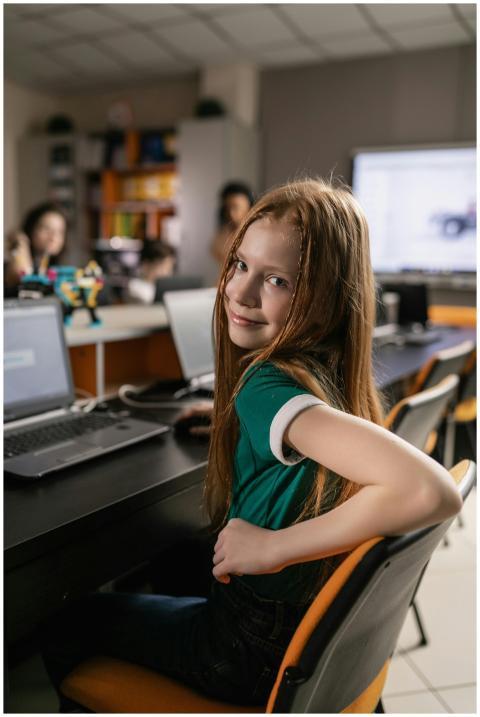 Teen girl smiling at camera while sitting at desk