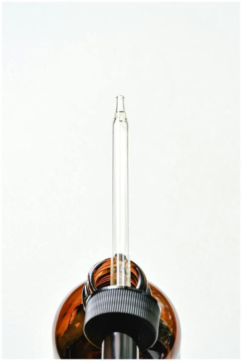 Minimalist image of a glass dropper in an amber bo
