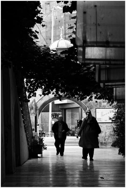 Monochrome image of people walking through an urba