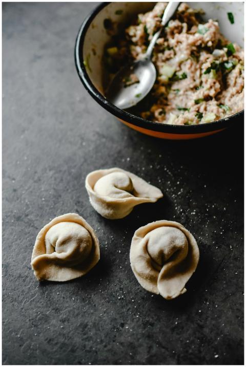 Close-up of uncooked dumplings next to a bowl of m