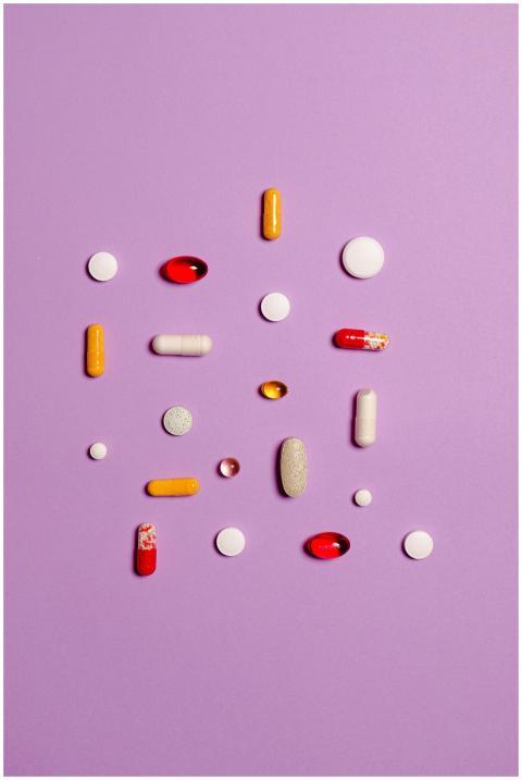 Variety of pills and capsules arranged on a purple