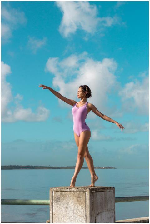 Elegant ballerina in pink leotard dancing outdoors