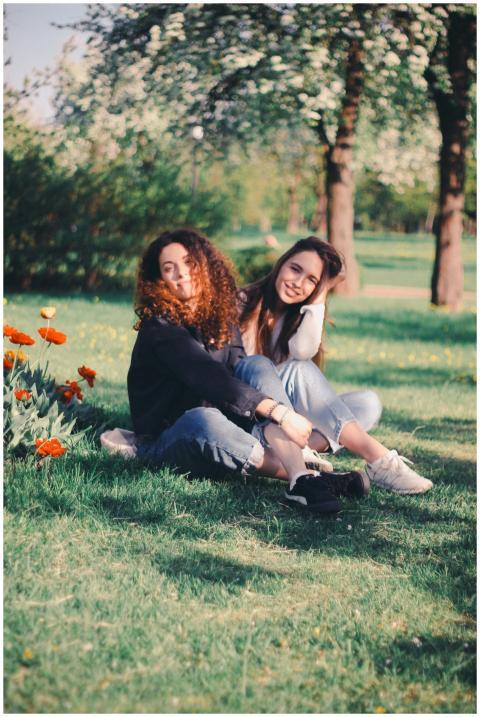 Two young women sitting on green grass surrounded