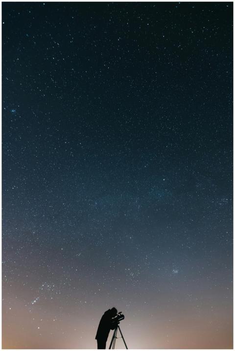 A lone astronomer using a telescope to observe the