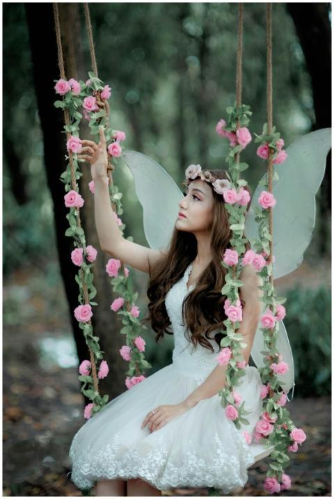 A fairy dressed in white, sitting on a flower-ador