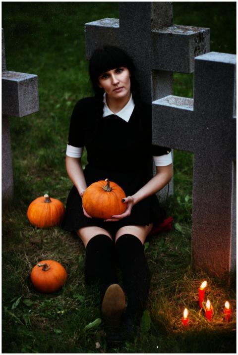 Gothic woman sitting in a graveyard holding a pump
