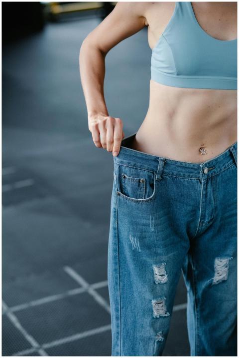 Woman in gym holding large jeans to show significa