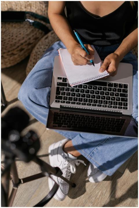 Person taking notes while studying online using a