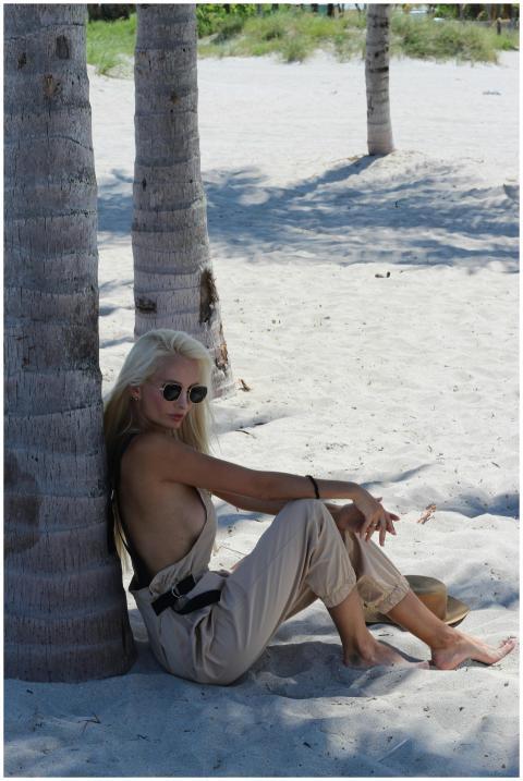Young woman in summer wear lounging by palm trees
