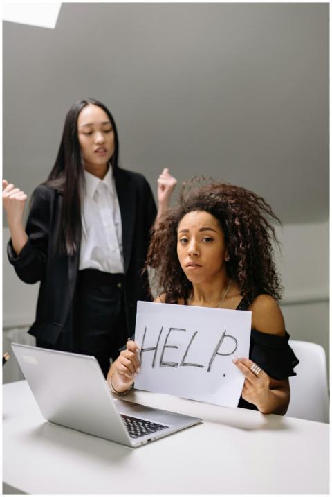 A woman holding a help sign, depicting workplace h