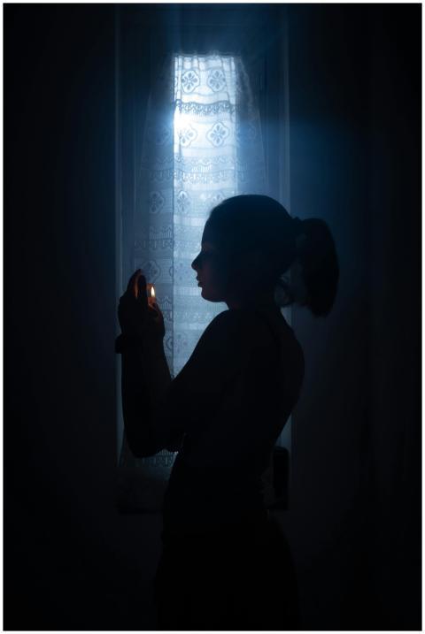 Artistic silhouette of a woman holding a candle, i
