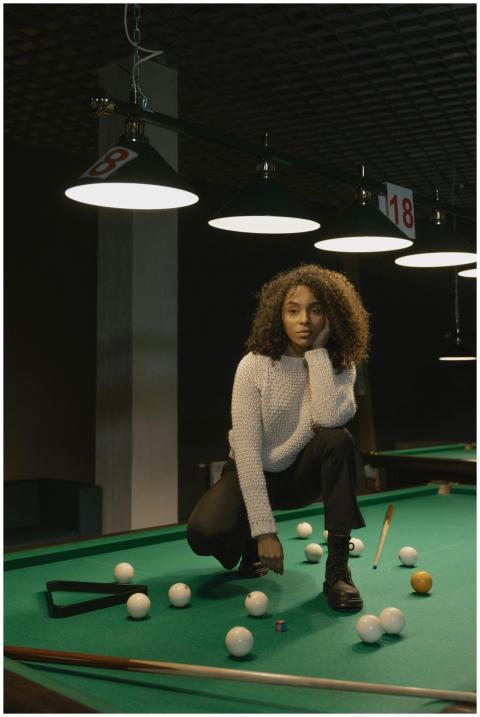 Woman with curly hair posing on a billiard table i