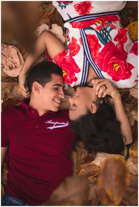 A happy couple lying on autumn leaves, embracing a