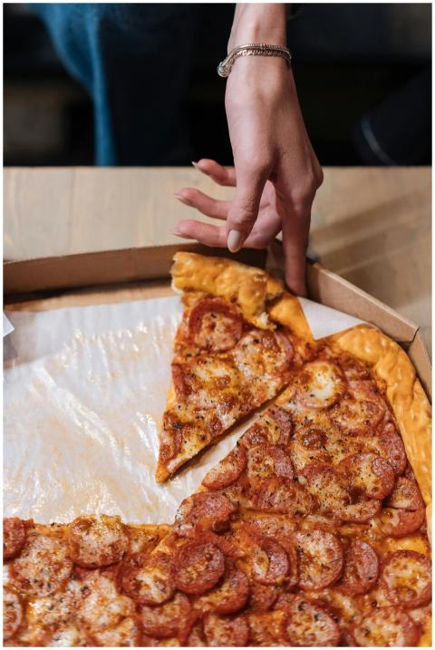 A hand reaches for a slice of delicious pepperoni
