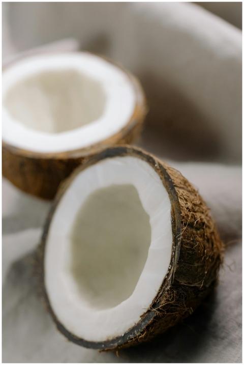 Close-up of fresh, cracked coconut halves on a sof