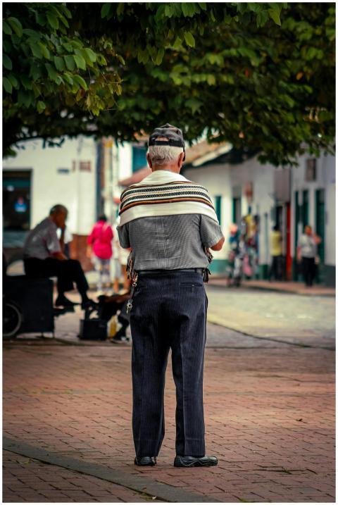 A senior man observed from behind in a lively city