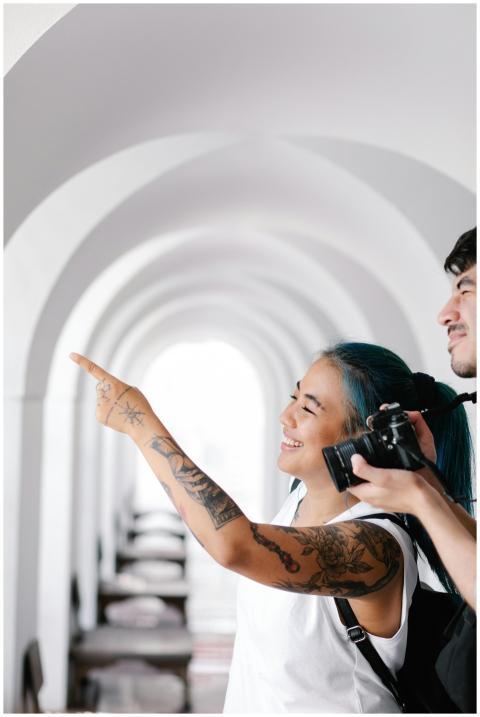 Smiling couple with tattoos exploring arches, came