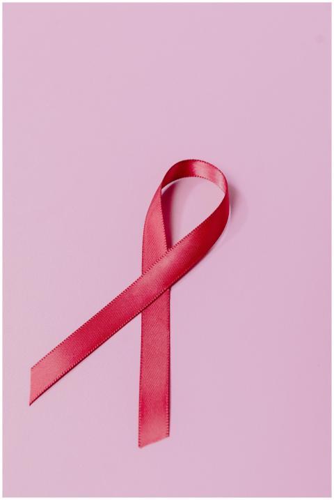 A pink ribbon on a pastel background symbolizing b