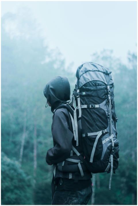 Solo hiker with large backpack in a misty forest,