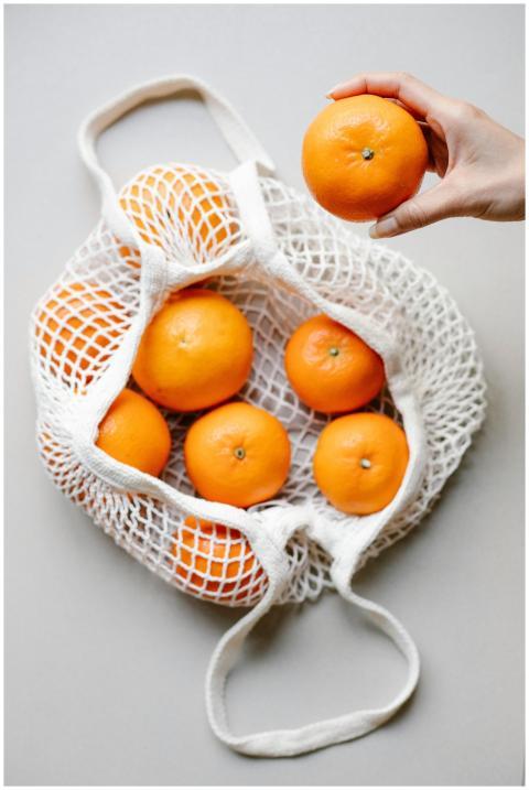 A mesh bag filled with fresh oranges, emphasizing