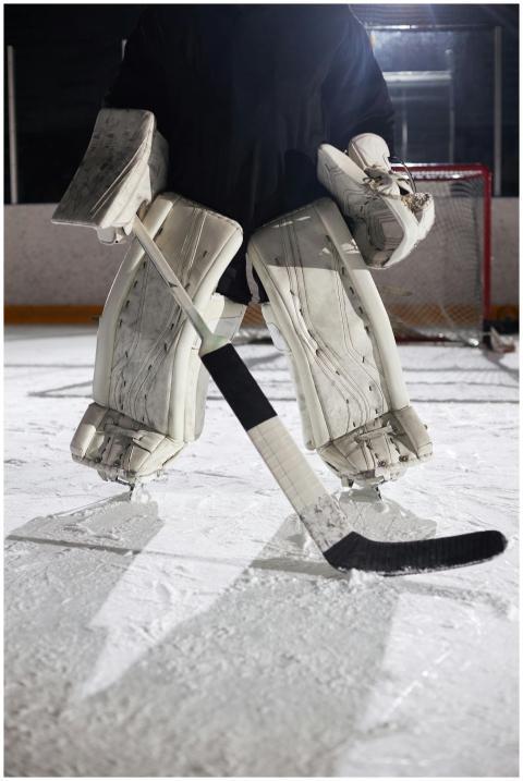 Hockey goalie standing on ice rink in full protect