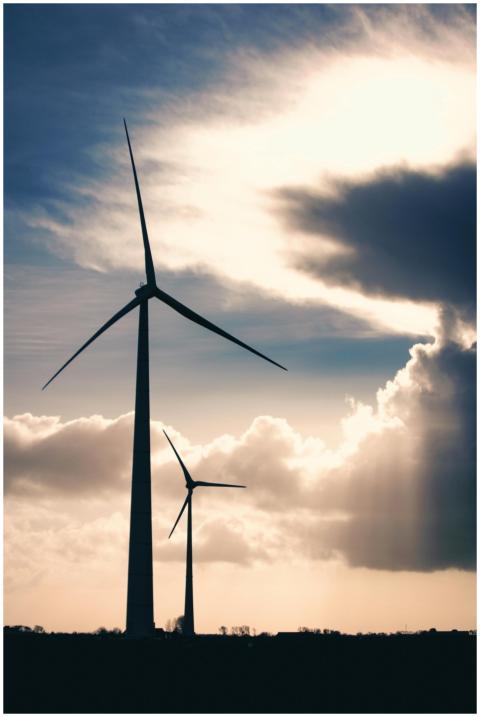 Silhouettes of wind turbines against a cloudy, dra