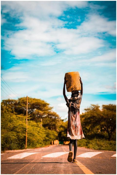 A young girl carries a container while walking on