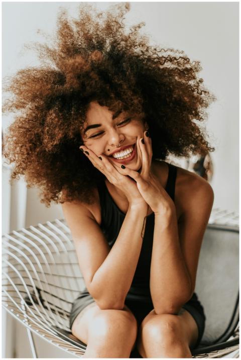A cheerful woman with an afro hairstyle sitting in