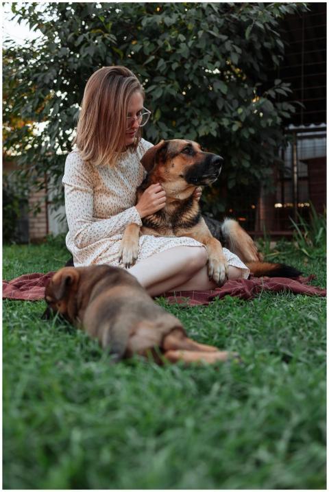 A woman sits on a blanket with her dogs in a seren
