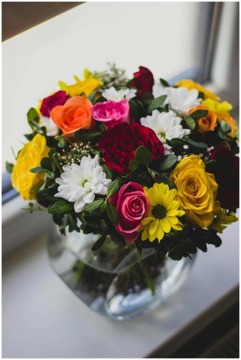 A colorful mix of roses and daisies in a glass vas